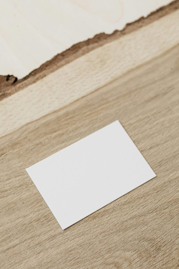 Minimalist blank business card placed on a textured wooden surface with ample copy space.
